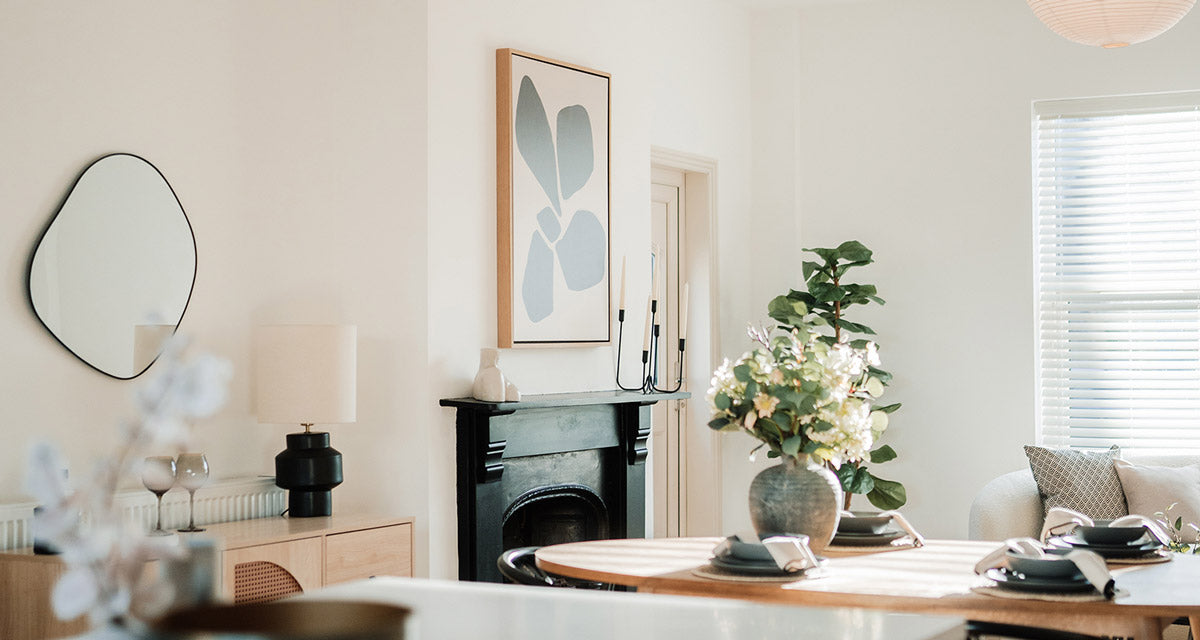 Square botanical framed canvas art above blue sofa in living room
