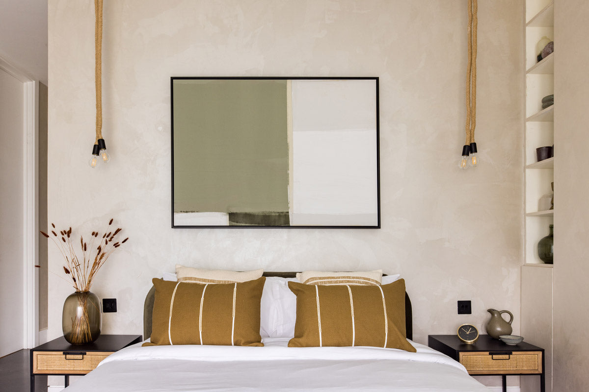 Green minimal abstract wall art hanging above a bed in a boho bedroom with mustard pillows and textured walls